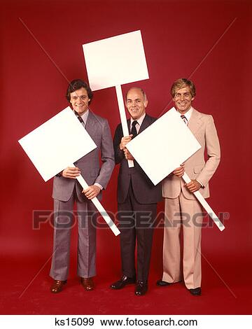 1970 1970S Three Businessmen Men Wearing Business Suits Each Carrying Blank Sign Placard Message Protest  View Large Photo Image Stock Photo - 1970 1970S Three Businessmen Men Wearing Business Suits Each Carrying Blank Sign Placard Message Protest . Fotosearch