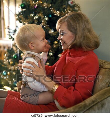 1970 1970S Woman Mother Smiling Baby Lap Parent Parenting Christmas Tree Holiday Baby First Family Families Retro View Large Photo Image Stock Photography - 1970 1970S Woman Mother Smiling Baby Lap Parent Parenting Christmas Tree Holiday Baby First Family Families Retro . Fotosearch