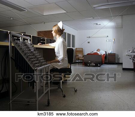Stock Photography - 1970 1970S Woman Night Nurse Sitting At Nurses Station In Intensive Care Hospital Unit . Fotosearch