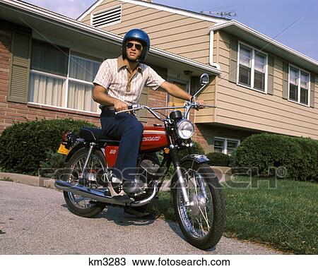 1970 1970S Young Man Blue Helmet Sitting On Motorcycle In Driveway Suburban House Bike Motorcycles Men View Large Photo Image Stock Image - 1970 1970S Young Man Blue Helmet Sitting On Motorcycle In Driveway Suburban House Bike Motorcycles Men . Fotosearch