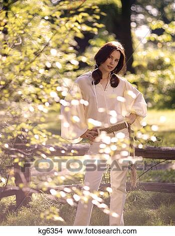 1970 1970S Young Woman Outdoors Spring White Hip Hugger Jeans Macrame Belt White Sheer Blouse Shirt Fashion View Large Photo Image Picture - 1970 1970S Young Woman Outdoors Spring White Hip Hugger Jeans Macrame Belt White Sheer Blouse Shirt Fashion . Fotosearch