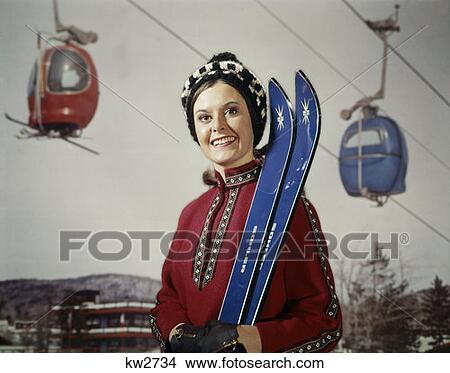 1970S 1970 Smiling Brunette Woman In Red Top Holding Blue Skis By Ski Lift Studio Retro Skiing View Large Photo Image Picture - 1970S 1970 Smiling Brunette Woman In Red Top Holding Blue Skis By Ski Lift Studio Retro Skiing. Fotosearch