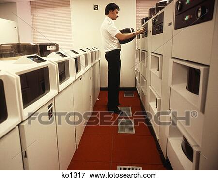 1970S 1980S Computer Technician Change Reel On Main Frame Computer Red & White Room View Large Photo Image Stock Photo - 1970S 1980S Computer Technician Change Reel On Main Frame Computer Red & White Room . Fotosearch