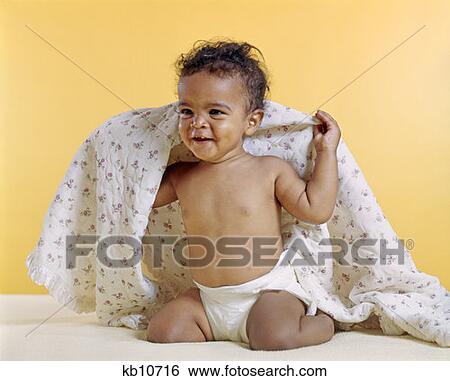 Stock Photograph - 1970S African-American Baby Smiling Holding Blanket Over Shoulders. Fotosearch