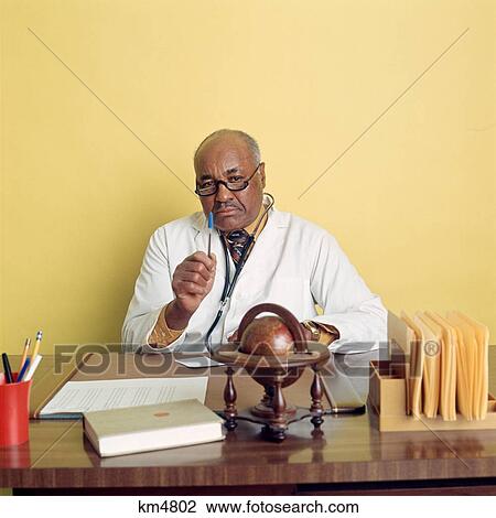 Stock Image - 1970S African American Doctor Sitting At Desk. Fotosearch