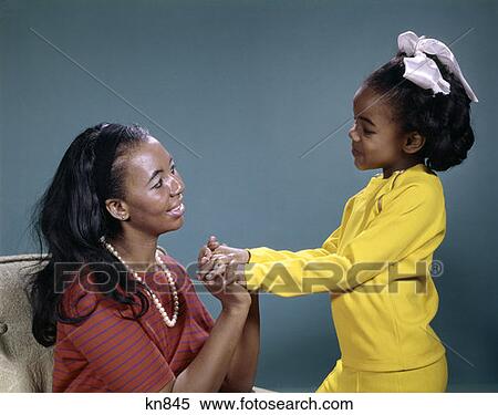 1970S African-American Ethnic Mother & Daughter Talking Hands Joined Mom In Red Stripe Top Pearls Girl In Yellow Outfit View Large Photo Image Stock Photography - 1970S African-American Ethnic Mother & Daughter Talking Hands Joined Mom In Red Stripe Top Pearls Girl In Yellow Outfit. Fotosearch
