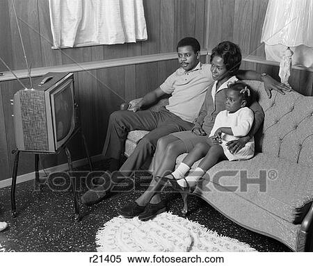 Stock Photography - 1970S African-American Family Watching Portable Television Mother Father Girl Sitting On Couch. Fotosearch