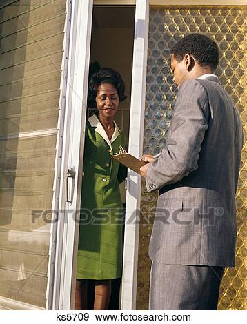 1970S African-American Salesman Man Hold Clipboard Talk To Woman Front Door Green Dress Door To Door Survey Census View Large Photo Image Stock Photo - 1970S African-American Salesman Man Hold Clipboard Talk To Woman Front Door Green Dress Door To Door Survey Census. Fotosearch