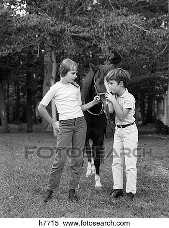 1970S Boy & Girl Standing Outside Holding Pony By Bridle View Large Photo Image Stock Photography - 1970S Boy & Girl Standing Outside Holding Pony By Bridle . Fotosearch