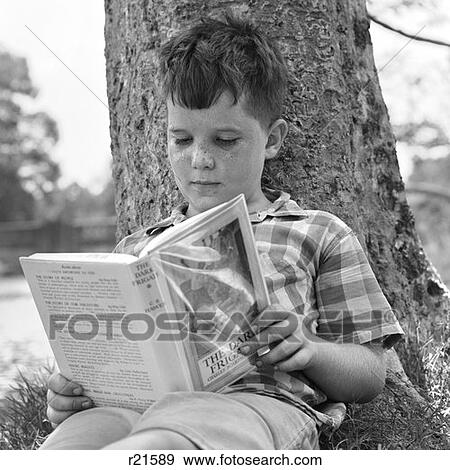 Stock Photo - 1970S Boy Leaning Against Tree Reading Book . Fotosearch