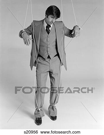 Stock Photograph - 1970S Businessman Puppet Strings Attached To Hands And Feet Weary Expression Indoor . Fotosearch