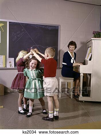 1970S Children Playing London Bridge Musical Game With Teacher Playing Piano Nostalgia View Large Photo Image Picture - 1970S Children Playing London Bridge Musical Game With Teacher Playing Piano Nostalgia . Fotosearch