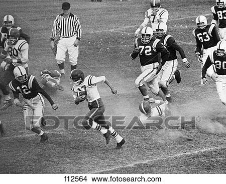 1970S Close-Up Of Football Game With Ball Carrier Surrounded By Members Of Opposing Team In Pursuit View Large Photo Image Picture - 1970S Close-Up Of Football Game With Ball Carrier Surrounded By Members Of Opposing Team In Pursuit . Fotosearch