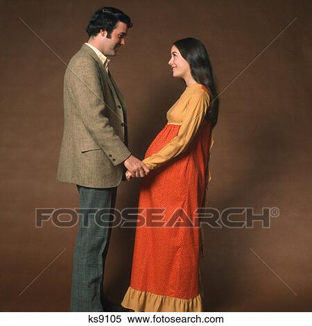 1970S Couple Man Pregnant Woman Standing Facing Each Other Holding Hands View Large Photo Image Stock Photography - 1970S Couple Man Pregnant Woman Standing Facing Each Other Holding Hands. Fotosearch