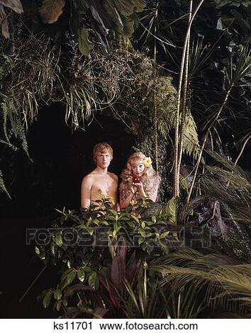1970S Couple Man Woman Adam Eve Silly Standing Jungle Foliage Holding Apple Sin Garden Of Eden Funny Character View Large Photo Image Stock Image - 1970S Couple Man Woman Adam Eve Silly Standing Jungle Foliage Holding Apple Sin Garden Of Eden Funny Character . Fotosearch