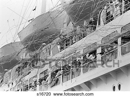 Stock Image - 1970S Crowd Gathered On 2 Levels Of Deck Of Large Cruise Ship Waving Pompoms With Streamers Blowing . Fotosearch