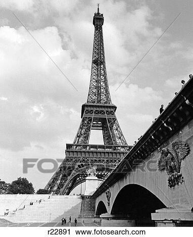 1970S Eiffel Tower With People Walking Up Stairs & Standing On Bridge Leading To It In Foreground View Large Photo Image Stock Image - 1970S Eiffel Tower With People Walking Up Stairs & Standing On Bridge Leading To It In Foreground . Fotosearch