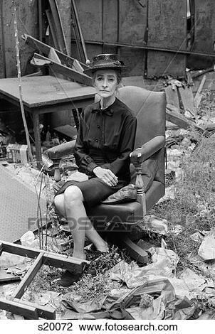 1970S Elderly Woman In Dress & Hat Sitting On Leather Swivel Chair Among Trash & Ruins With Morose Expression View Large Photo Image Stock Image - 1970S Elderly Woman In Dress & Hat Sitting On Leather Swivel Chair Among Trash & Ruins With Morose Expression . Fotosearch