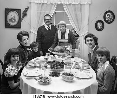 1970S Extended Family Sitting Around Dining Room Table With Grandmother Standing At Head Setting Down Turkey Platter View Large Photo Image Stock Photo - 1970S Extended Family Sitting Around Dining Room Table With Grandmother Standing At Head Setting Down Turkey Platter. Fotosearch