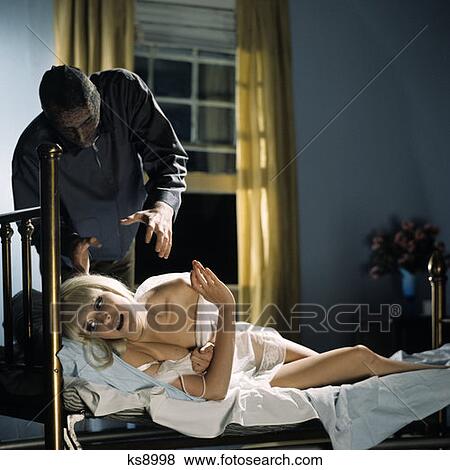 1970S Frightened Blonde Woman Brass Bed Attacked By Intruder Man Stocking Mask Hand Grabbing Reaching Strangle Murder View Large Photo Image Stock Photo - 1970S Frightened Blonde Woman Brass Bed Attacked By Intruder Man Stocking Mask Hand Grabbing Reaching Strangle Murder. Fotosearch
