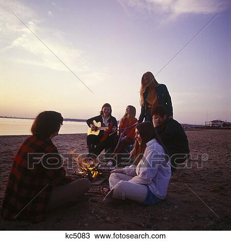 1970S Group Teenager Boys Girls Together Seashore Shore Campfire Guitar Singing Retro Sand Sunset Ocean Beach Outdoor View Large Photo Image Stock Image - 1970S Group Teenager Boys Girls Together Seashore Shore Campfire Guitar Singing Retro Sand Sunset Ocean Beach Outdoor. Fotosearch