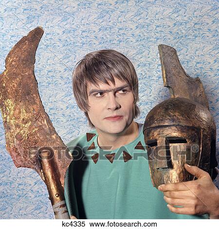 Stock Photography - 1970S Man Actor Costume Greek Tragedy Looking To Side Holding Mask Helmet Blade Lance. Fotosearch
