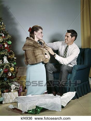 1970S Man Adjusting New Fur Jacket On Wife In Living Room Beside Christmas Tree Indoor Gift Holiday Lifestyle View Large Photo Image Stock Photograph - 1970S Man Adjusting New Fur Jacket On Wife In Living Room Beside Christmas Tree Indoor Gift Holiday Lifestyle . Fotosearch