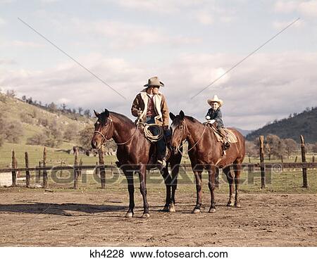 1970S Man And Boy Father And Son Cowboy Sitting Together On Horses By Corral Wearing Hats In California View Large Photo Image Stock Photo - 1970S Man And Boy Father And Son Cowboy Sitting Together On Horses By Corral Wearing Hats In California. Fotosearch
