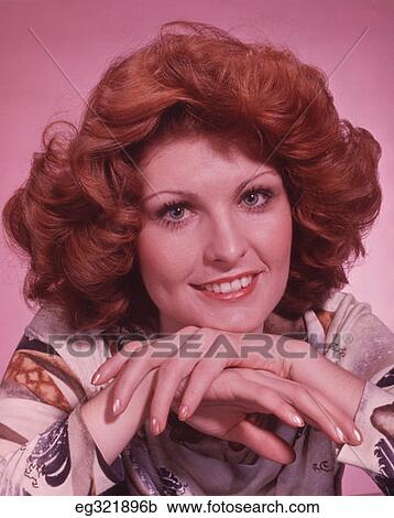 Stock Image - 1970S Portrait Smiling Red Haired Woman Hands Folded By Chin. Fotosearch