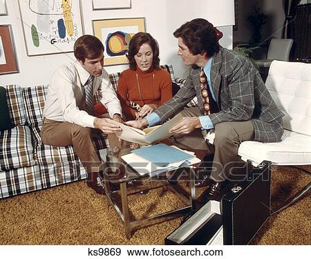1970S Retro Insurance Salesman Showing Policy To Husband Wife Man Woman Couple Sitting On Couch In Living Room View Large Photo Image Stock Photo - 1970S Retro Insurance Salesman Showing Policy To Husband Wife Man Woman Couple Sitting On Couch In Living Room. Fotosearch