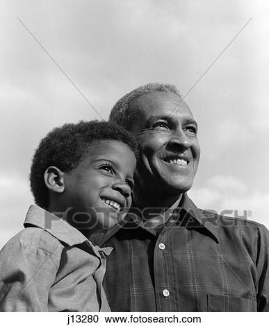1970S Smiling Black Boy & Grandfather With Arms Around Each Other Looking Off Into Distance View Large Photo Image Stock Image - 1970S Smiling Black Boy & Grandfather With Arms Around Each Other Looking Off Into Distance . Fotosearch