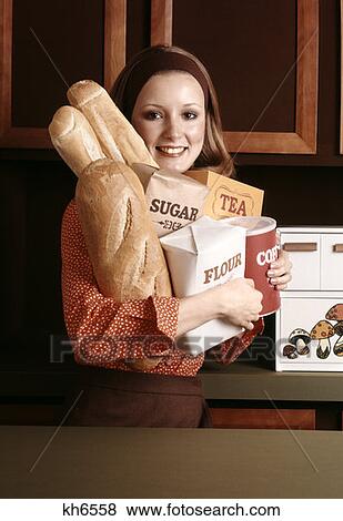1970S Smiling Woman Housewife Arm Full Of Basic Kitchen Food Supplies Bread Flour Sugar Tea Coffee Staples Groceries View Large Photo Image Stock Photo - 1970S Smiling Woman Housewife Arm Full Of Basic Kitchen Food Supplies Bread Flour Sugar Tea Coffee Staples Groceries . Fotosearch
