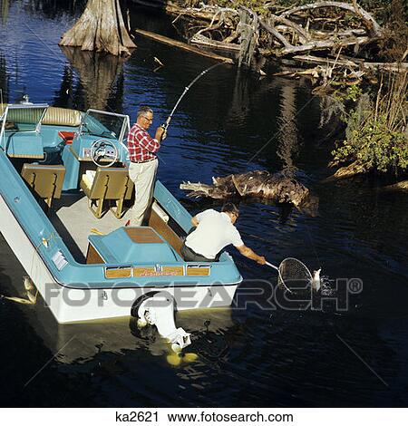 1970S Two Elderly Men Fishing In Cypress Swamp Off Blue White Motor Boat Outboard One Man Rod Reel Other Nets Net Fish View Large Photo Image Stock Image - 1970S Two Elderly Men Fishing In Cypress Swamp Off Blue White Motor Boat Outboard One Man Rod Reel Other Nets Net Fish. Fotosearch