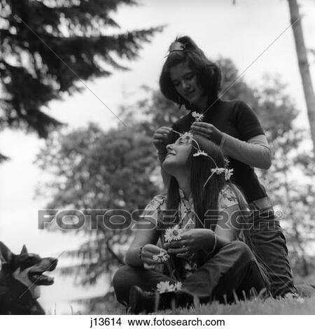 1970S Two Teen Hippie Girls Outdoors Sitting In Grass One Is Putting Flowers In Others Hair View Large Photo Image Picture - 1970S Two Teen Hippie Girls Outdoors Sitting In Grass One Is Putting Flowers In Others Hair. Fotosearch