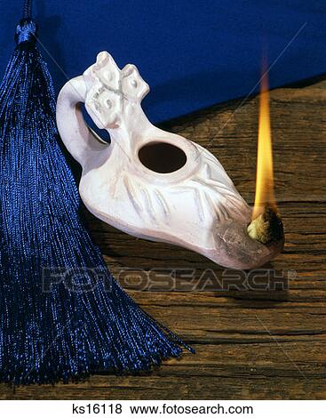 Stock Photo - 1970S White Lamp Lantern Of Knowledge Education With Flame On Wooden Table Top With Blue Graduation Cap Tassel. Fotosearch