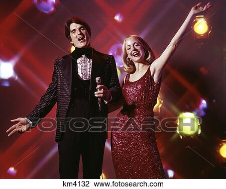1970S Woman And Man With Microphone Singing And Gesturing Strobe Lights In Background Tuxedo Gown Entertain View Large Photo Image Stock Image - 1970S Woman And Man With Microphone Singing And Gesturing Strobe Lights In Background Tuxedo Gown Entertain . Fotosearch