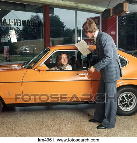 1970S Woman Driving Orange Car Getting Service From Man In Business Suit Help Talking Salesman View Large Photo Image Stock Image - 1970S Woman Driving Orange Car Getting Service From Man In Business Suit Help Talking Salesman. Fotosearch