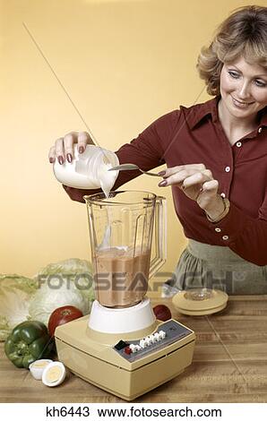 Stock Image - 1970S Woman Pouring Mayonaise Into Hamilton Beach Blender Making Salad Dressing For Vegetables . Fotosearch