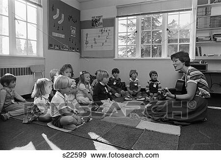 1980S Grade School Teacher Sitting On Floor With Students Playing Guitar & Singing View Large Photo Image Stock Photo - 1980S Grade School Teacher Sitting On Floor With Students Playing Guitar & Singing . Fotosearch