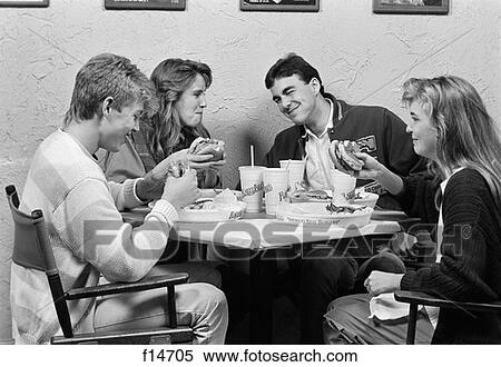 1980S Group Of Two Male & Two Female Teens Sitting Around Table At Restaurant Chatting & Eating Hamburgers View Large Photo Image Stock Photography - 1980S Group Of Two Male & Two Female Teens Sitting Around Table At Restaurant Chatting & Eating Hamburgers . Fotosearch