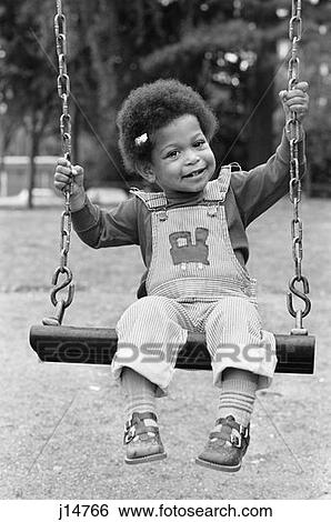 1980S Little African-American Girl In Overalls Sitting On Swing View Large Photo Image Stock Photograph - 1980S Little African-American Girl In Overalls Sitting On Swing . Fotosearch