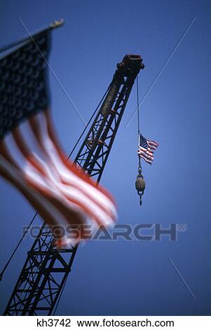 Stock Image - American Flag Flying From Construction Crane Boom Industry Symbolic. Fotosearch