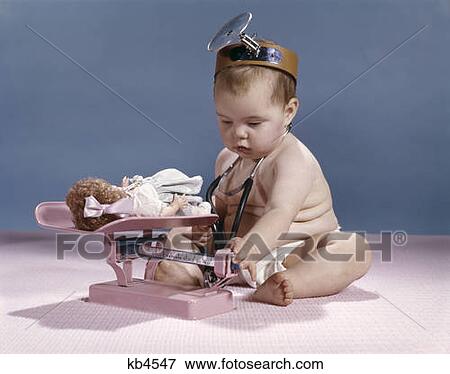 Stock Photo - Baby With Physician Mirror Headband Weighing Doll On Infant Balance Scale Studio . Fotosearch