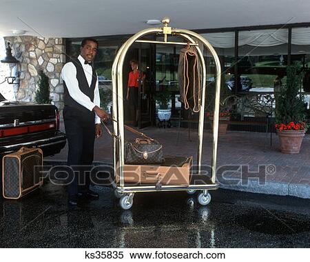Stock Photography - Bellman Helping With Luggage On Hotel Cart Smiling Radnor, Pennsylvania. Fotosearch
