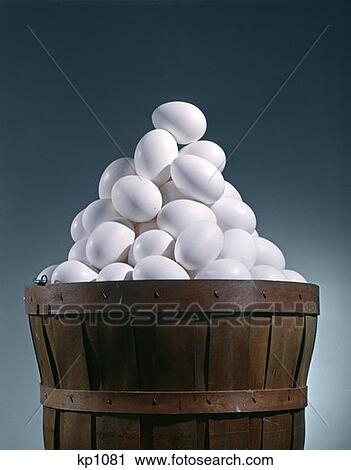 Stock Image - Brown Wooden Bushel Basket Full Of White Chicken Eggs In 1 Basket Pyramid Shape Triangle. Fotosearch