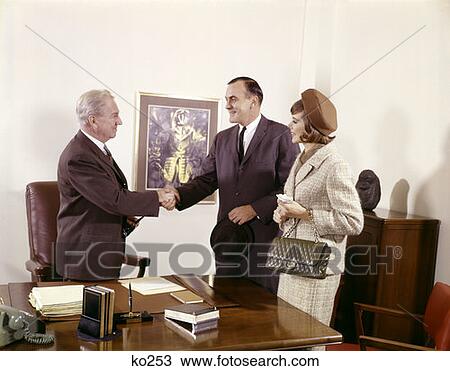 Couple Standing At Desk With Executive Men Shaking Hands Indoor Man Woman Three Bank Loan View Large Photo Image Stock Image - Couple Standing At Desk With Executive Men Shaking Hands Indoor Man Woman Three Bank Loan . Fotosearch