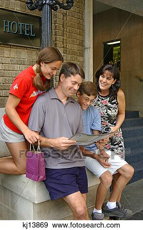 Stock Photo - Family Of Four Reading Magazine, Tourists. Fotosearch