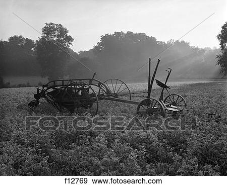 Farm Scene With Old Hay Baler In Middle Of Field & Rays Of Sun Coming Through At Dawn View Large Photo Image Stock Photo - Farm Scene With Old Hay Baler In Middle Of Field & Rays Of Sun Coming Through At Dawn . Fotosearch