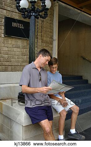 Stock Photograph - Father And Son Reading Magazine, Tourists. Fotosearch