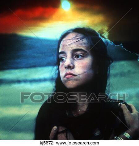 Stock Image - Girl Teenager Long Hair Bowing In Wind Sunset In Background 1970 1970S. Fotosearch